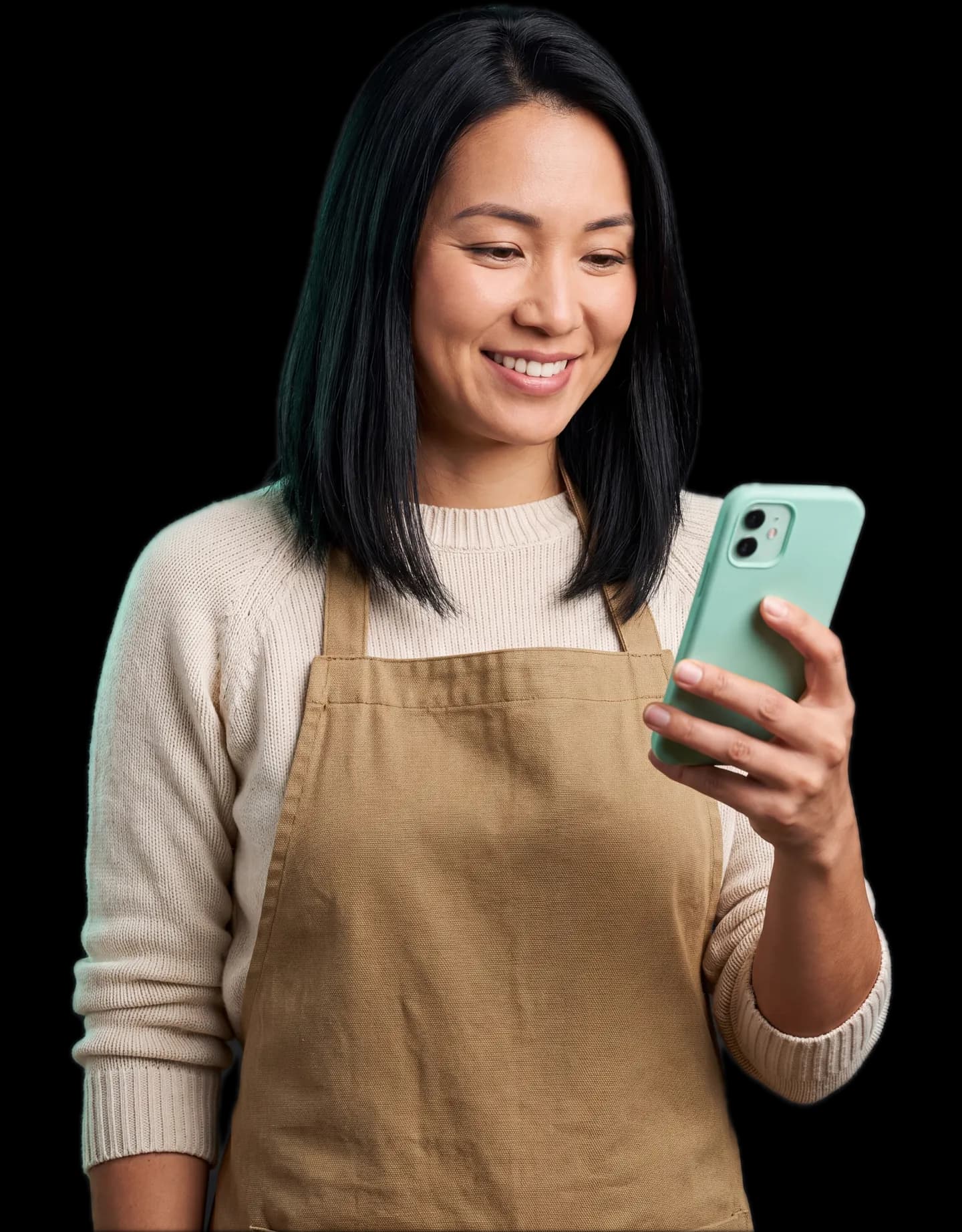 Dona de loja de avental sorrindo enquanto lê o pedido de uma cliente no celular